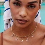 A woman wearing a necklace with small moons hanging off.