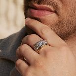 A man touching his chin with a thick jeweled band.