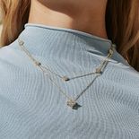 A woman with a blue mock turtleneck wearing two necklaces.